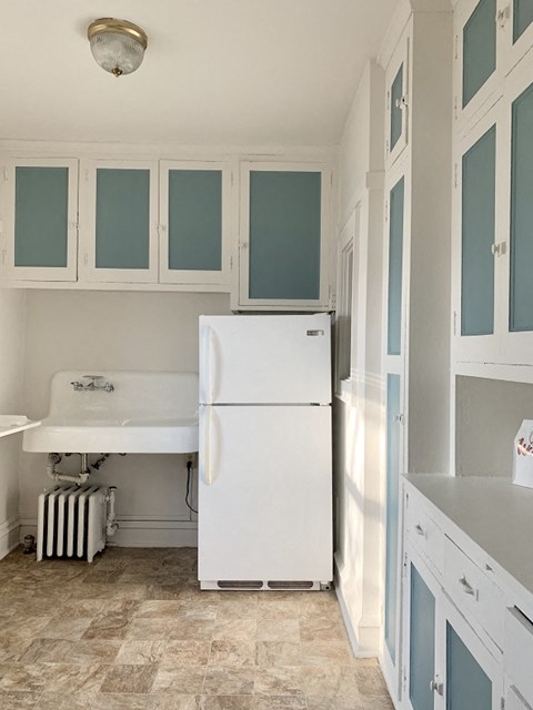a white kitchen with a refrigerator and a sink