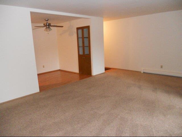 an empty living room with a ceiling fan