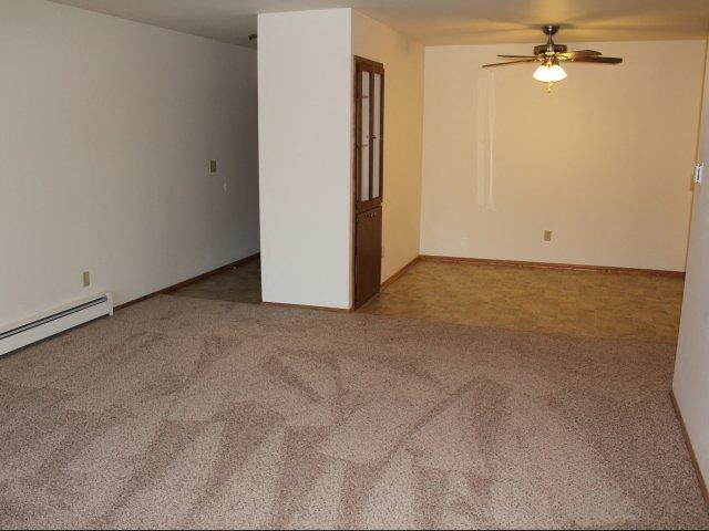 an empty living room with a ceiling fan