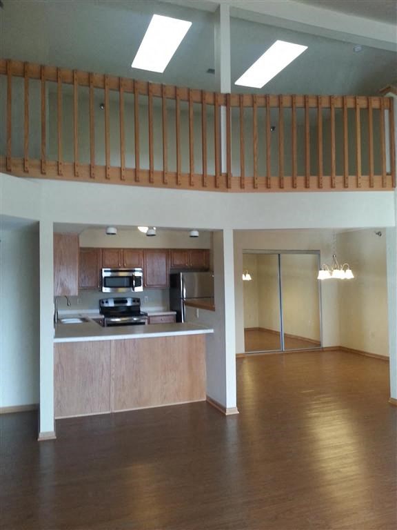 an empty living room with a kitchen and a loft