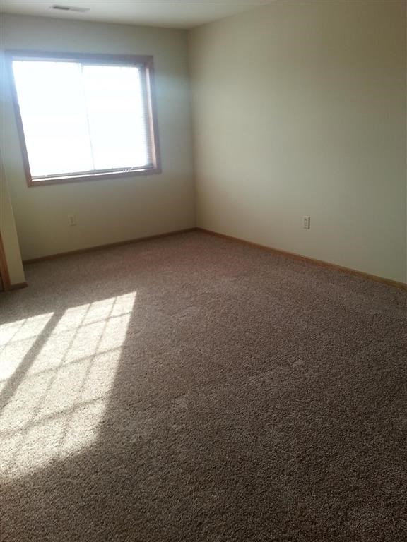an empty room with a window and carpet