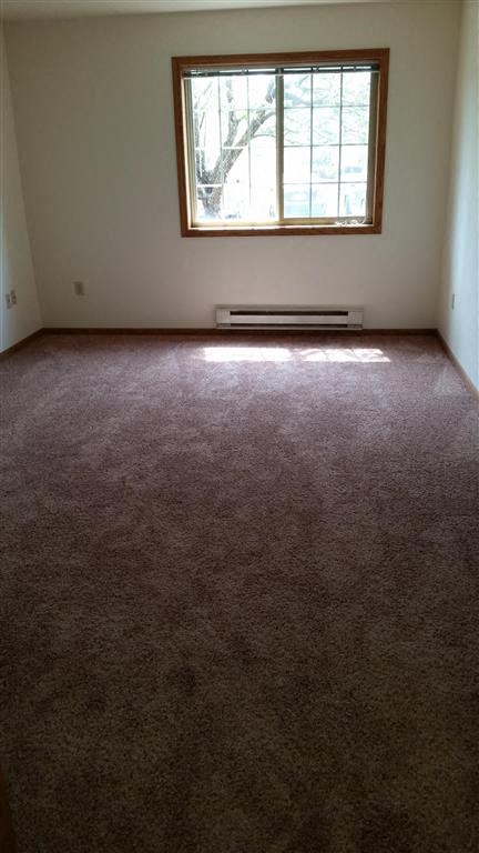 an empty room with a window and a carpeted floor