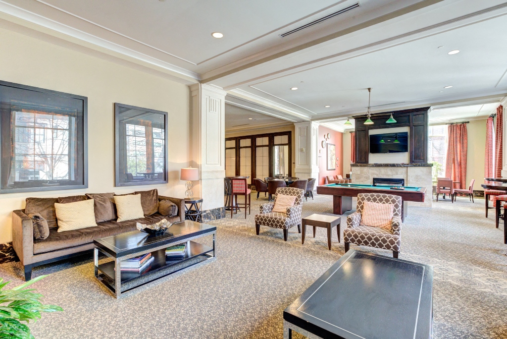 a living room with a couch and chairs and a pool table