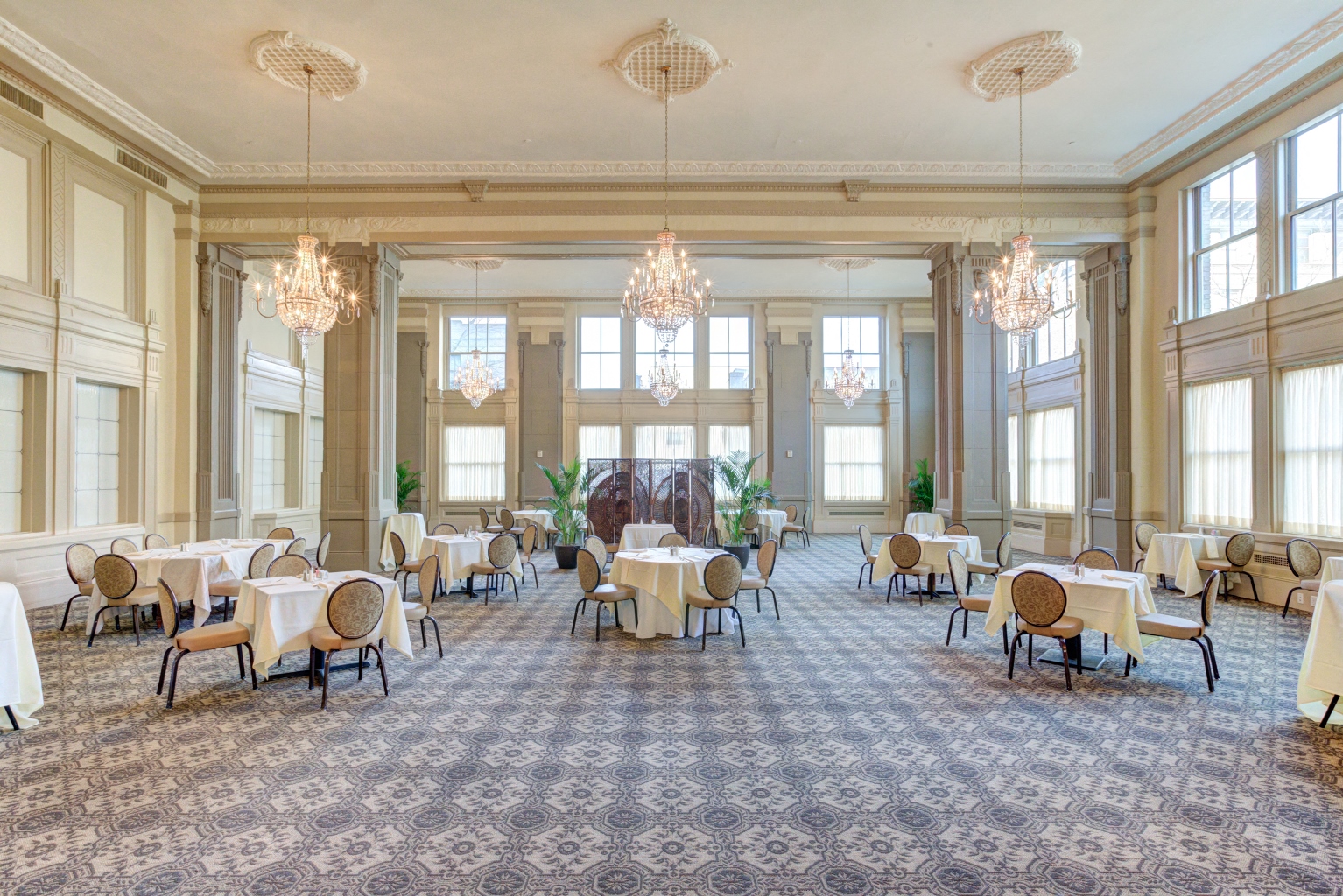 a large dining room with tables and chairs and chandeliers