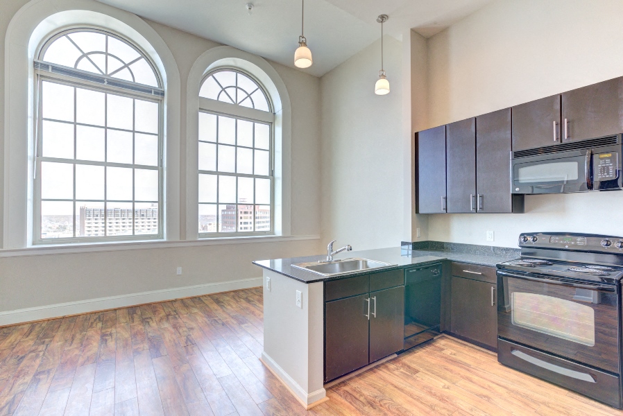 an empty kitchen with stainless steel appliances and wood floors