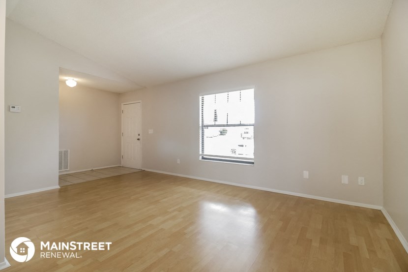 the spacious living room with wood flooring and a large window