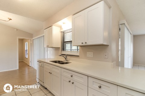 a kitchen with white cabinets and a sink and a window