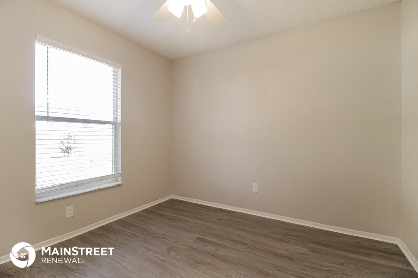 the upstairs bedroom with wood flooring and a window