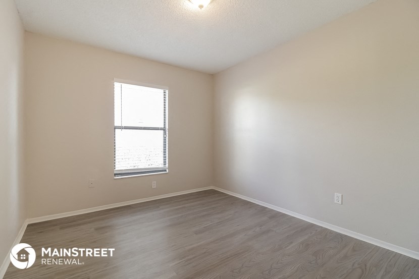 the spacious living room with wood flooring and a window