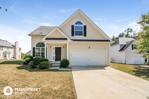 a beige house with a white garage door and a lawn