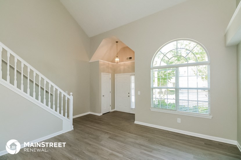 the entryway of a home with a large window and stairs
