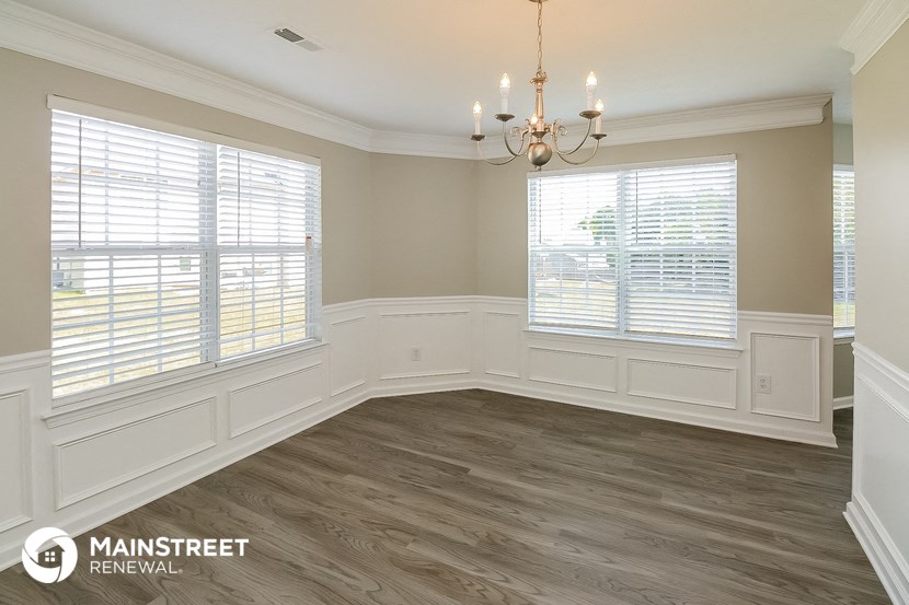 the living room after remodeling with wood flooring and a chandelier