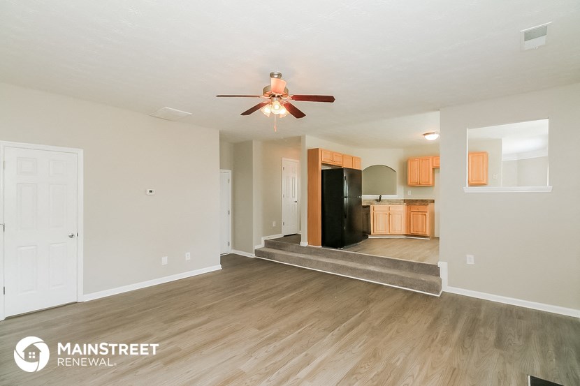 a living room with a ceiling fan and a kitchen