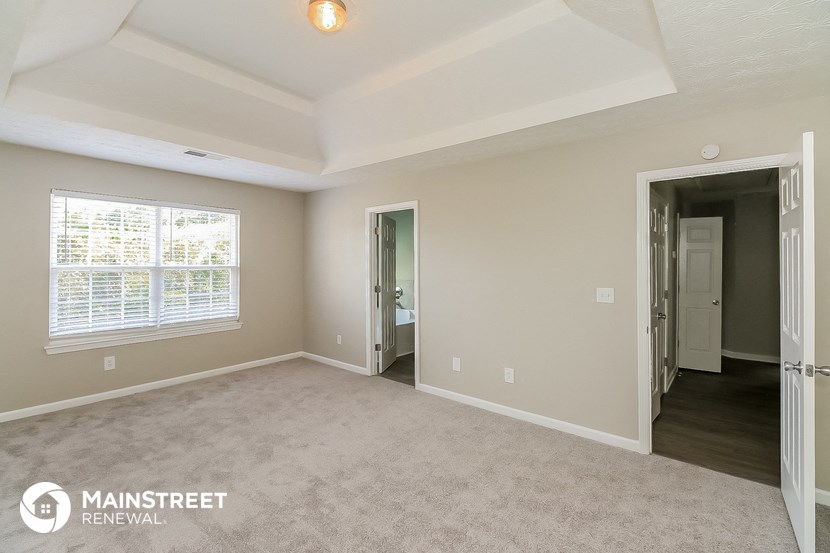 the living room of an apartment with a carpeted floor and a large window