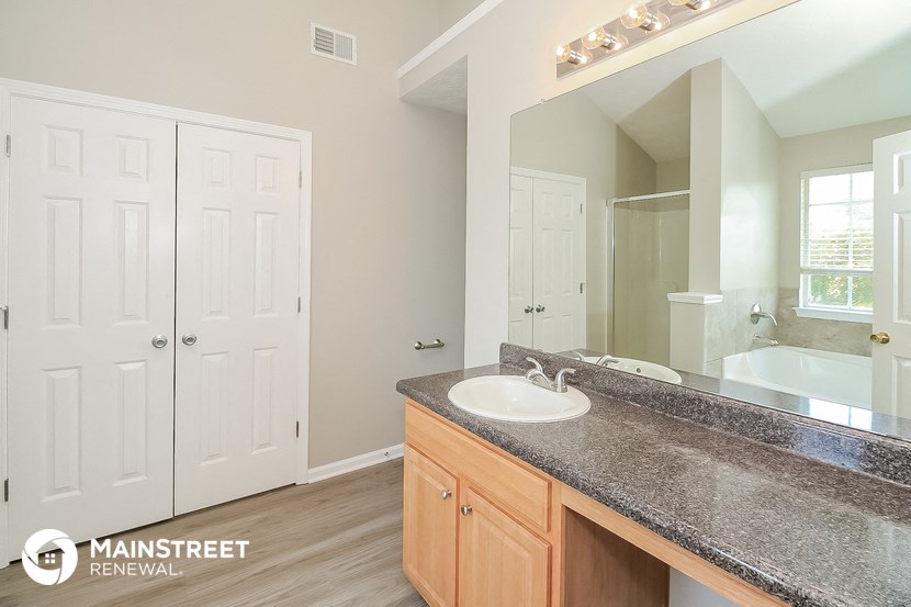 the master bathroom has a granite counter top and a large mirror