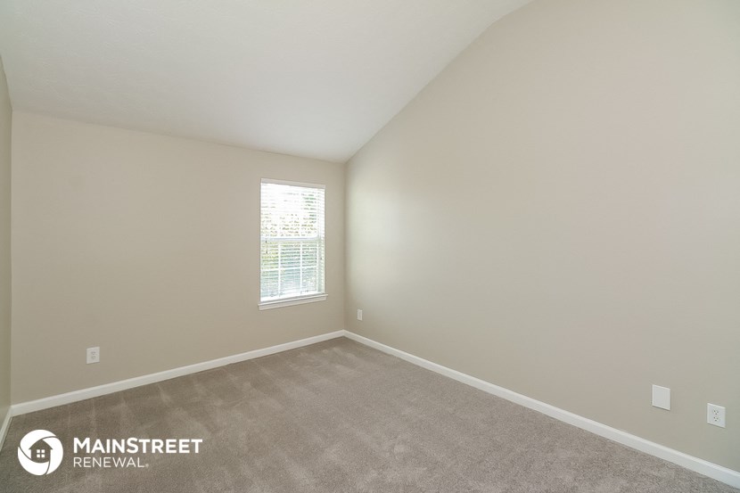 the spacious living room with carpeting and a window