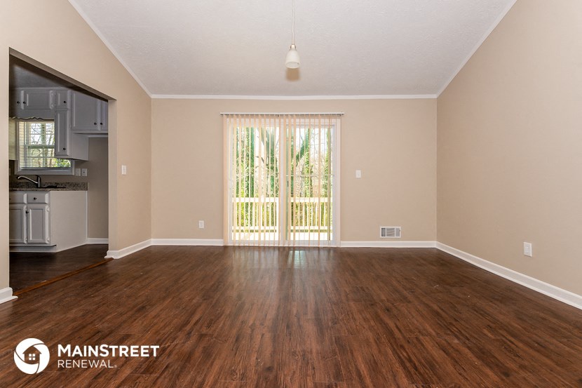 the spacious living room with hardwood flooring and sliding glass doors to the kitchen
