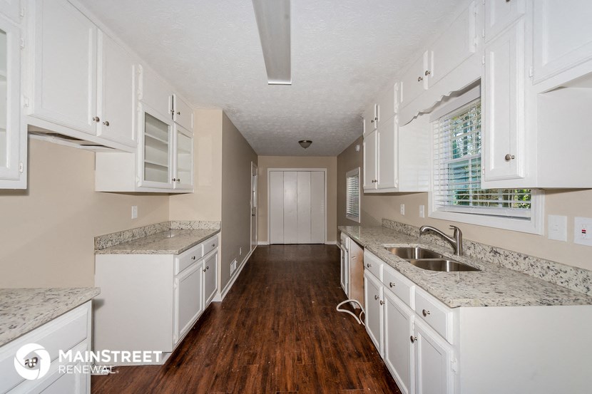 a kitchen with white cabinets and white counter tops and a wood floor