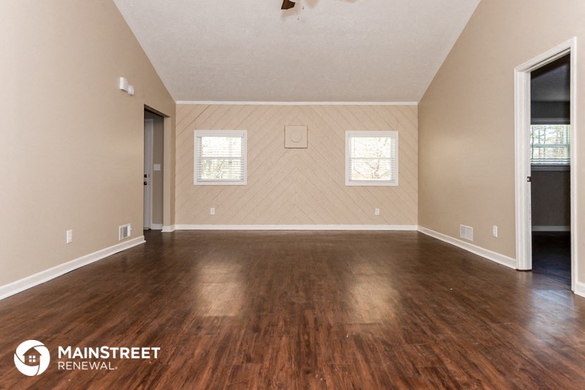 the spacious living room with hardwood flooring and a window