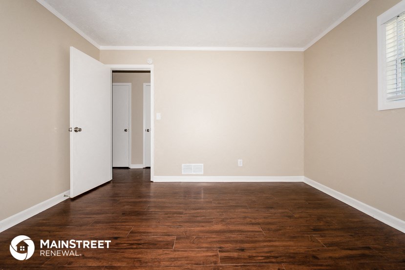 a living room with wood floors and white walls and a door