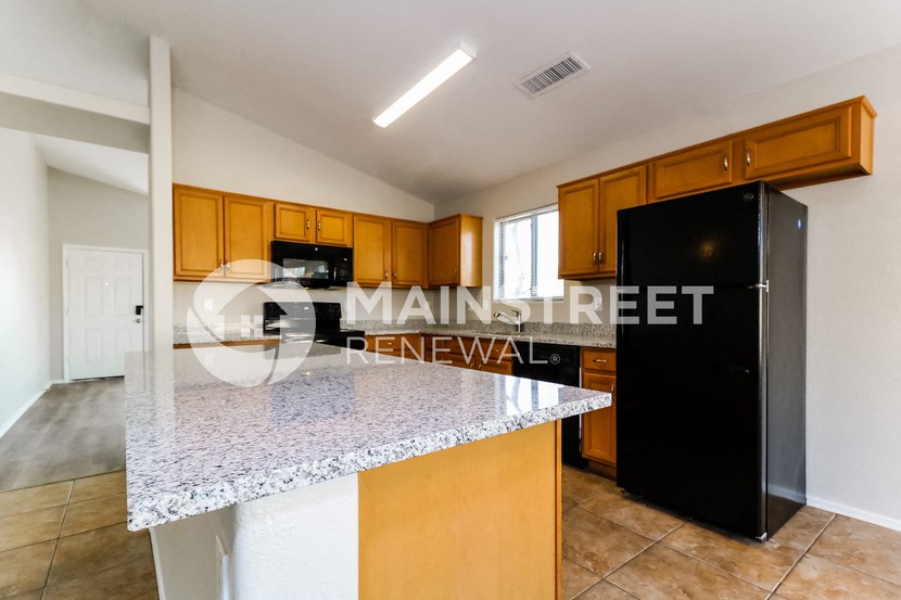 a kitchen with a granite counter top and a black refrigerator