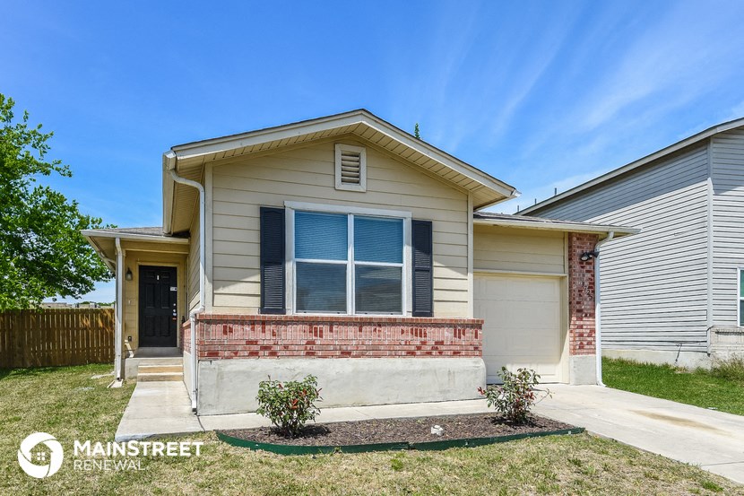 a tan house with a front porch and a blue sky