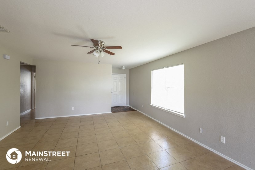 the spacious living room with ceiling fan and tiled floor