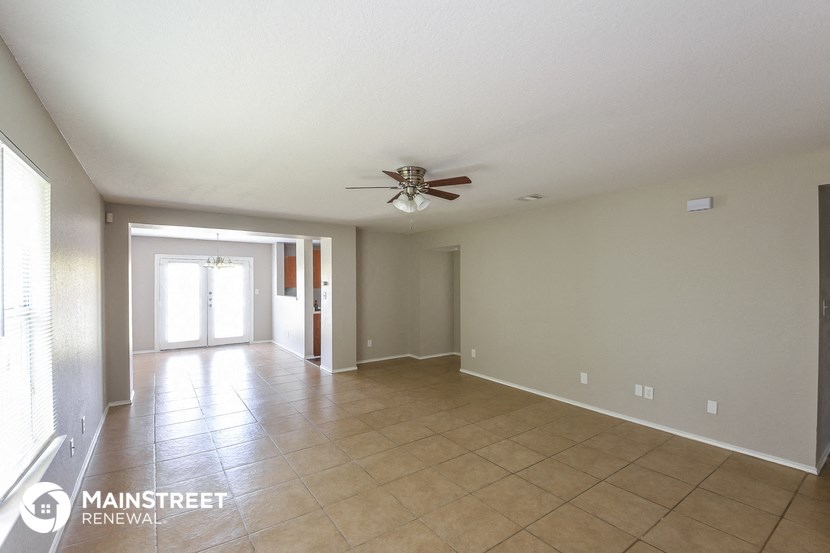 an empty living room with a ceiling fan
