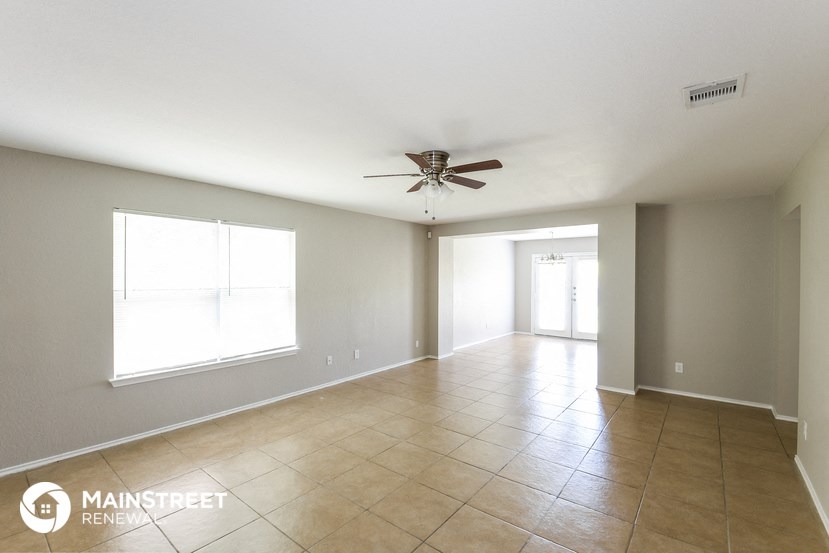 a large living room with tile flooring and a ceiling fan