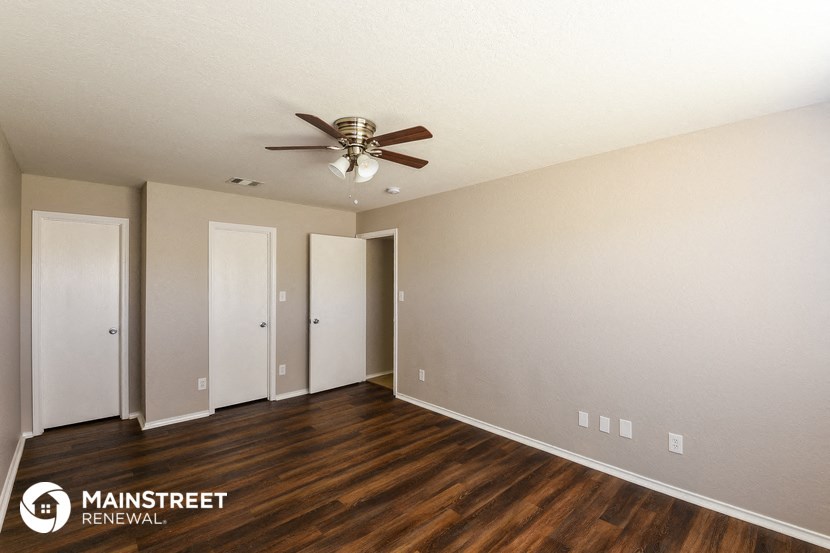 a living room with wood flooring and a ceiling fan