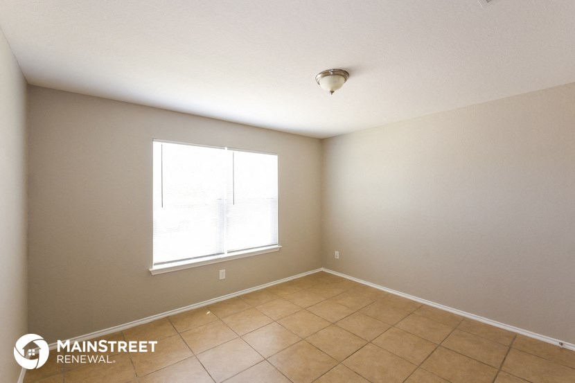 the living room of a home with a tiled floor and a window