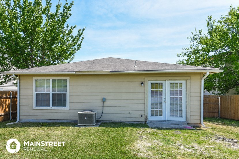 the front of a small tan house with two doors
