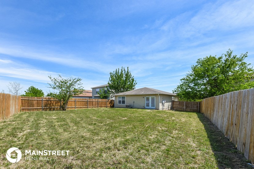 a backyard with a fence and a small house