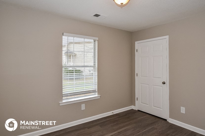 the bedroom of a house with a white door and a window
