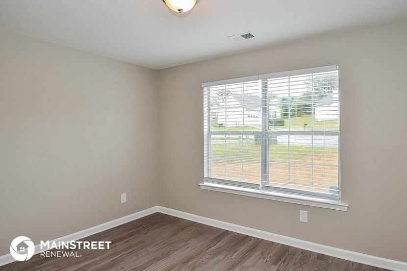 the spacious living room with a large window and wood flooring