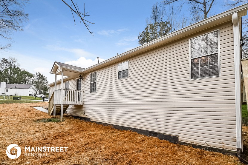 a side view of a white house with a porch and a deck