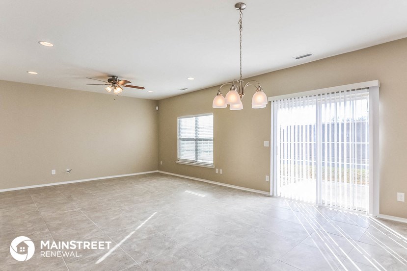 an empty living room with a ceiling fan and a window