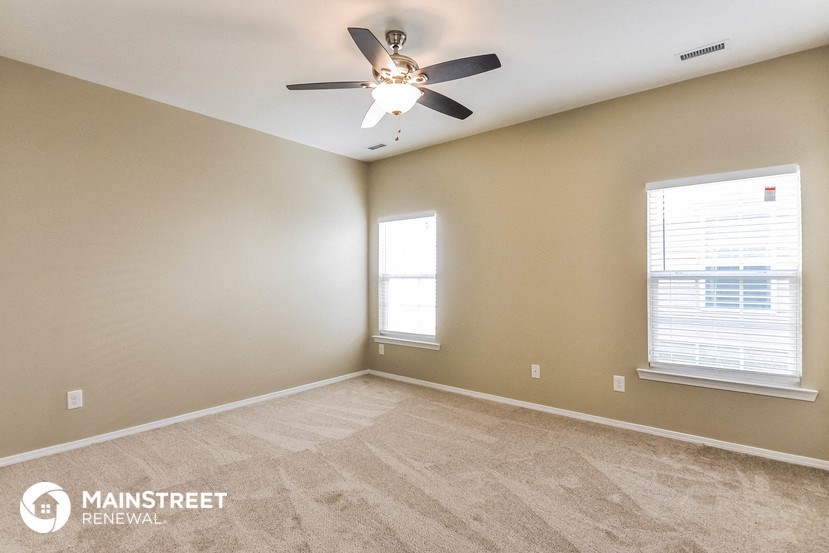 the living room is spacious and has a ceiling fan