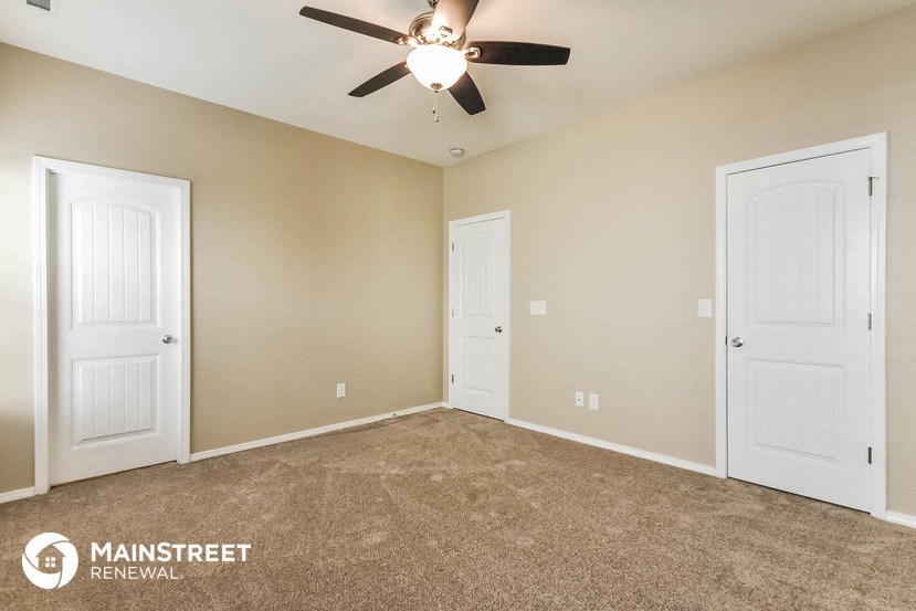 a bedroom with two doors and a ceiling fan