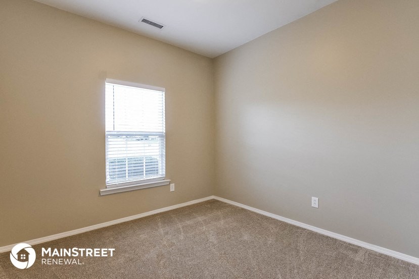 the living room of a home with a window and carpet