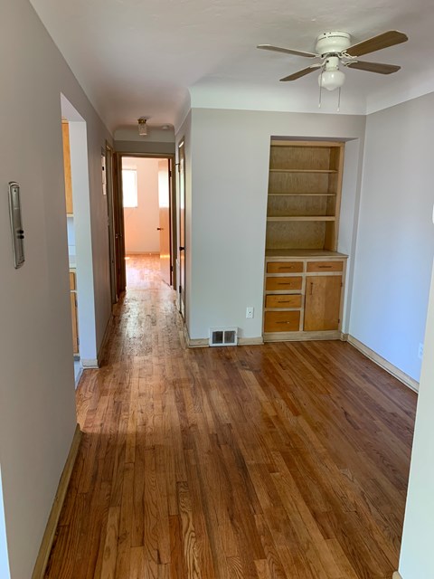 a living room with a wooden floor and a ceiling fan