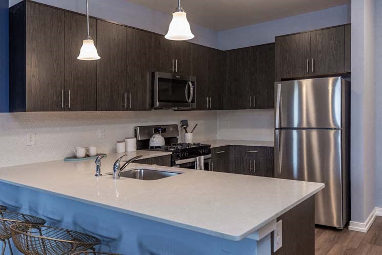 a kitchen with a white counter top and a stainless steel refrigerator