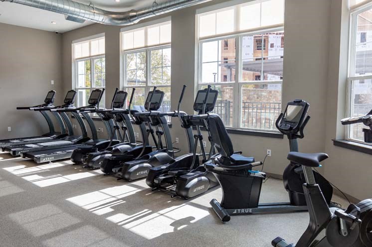 a row of exercise machines in a room with windows