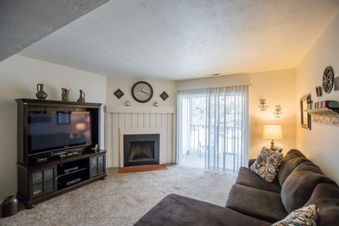 the living room has a large screen tv and a fireplace