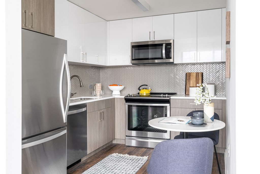 a small kitchen with stainless steel appliances and a white table