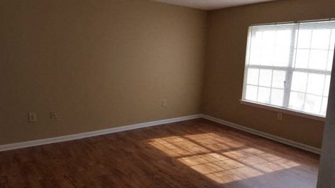 A room with a window and wooden flooring.