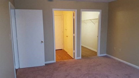 A room with a white door, a white closet door, and a white closet.