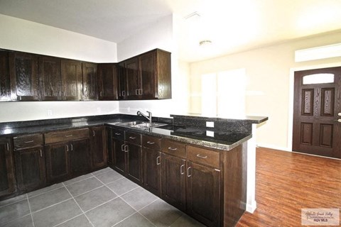 A kitchen with dark wood cabinets and a granite countertop.