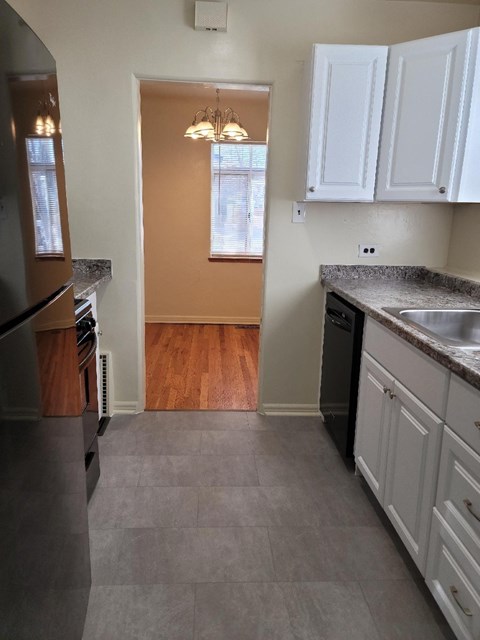 A kitchen with white cabinets and a black fridge.