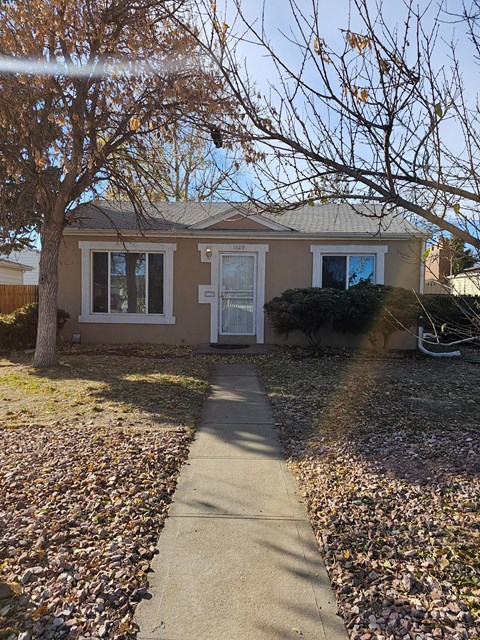 A house with a white door and a tree in front.